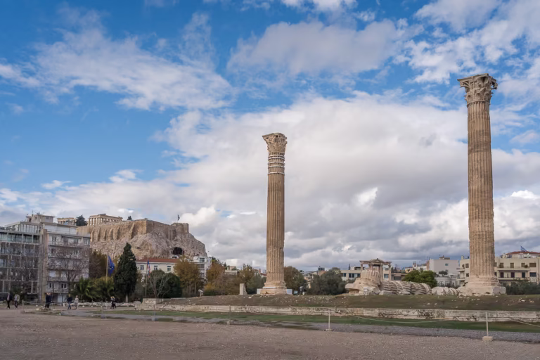 Two standing and one lied on the ground column in Olympieion. The Acropolis is in the background.